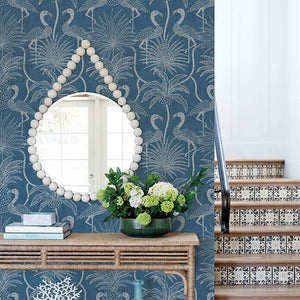Decorative interior with a console table, mirror, and floral arrangement against a blue patterned wall.