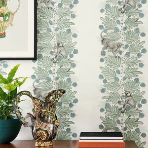 Decorative wallpaper with leaf pattern, plant, vase, and books on a table.