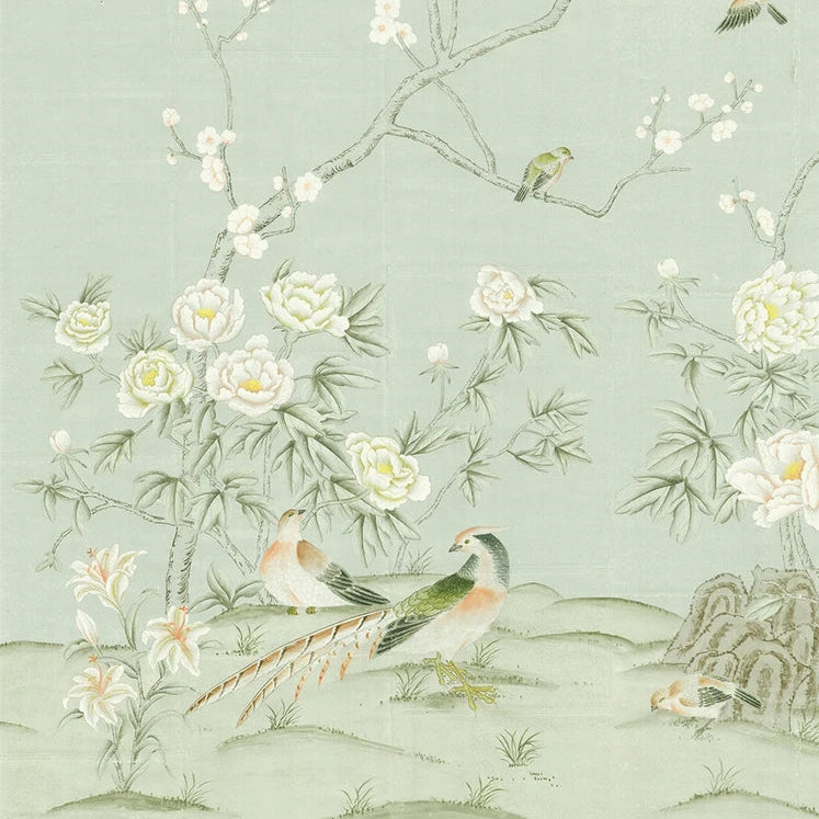 Chinoiserie wallpaper featuring delicate white flowers, green birds, and a pheasant on a pale sage green background. The design includes a branch with blossoms, small birds perched on branches, and a pheasant near the bottom center.