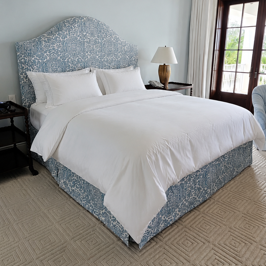 Bedroom with a neatly made bed featuring white bedding and a blue headboard.
