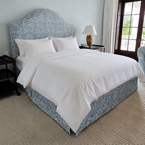 Bedroom with a neatly made bed featuring white bedding and a blue headboard.