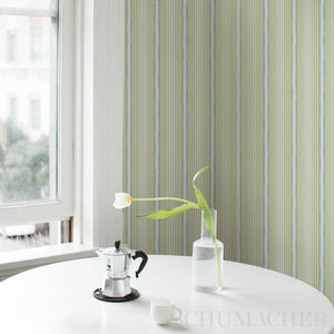 Striped wallpaper with a window and a small table with a tulip and coffee maker.