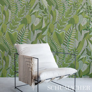 Modern chair with a white cushion against a green leafy patterned wall, featuring the Schumacher brand.