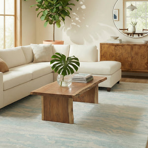 Living room with a white sofa, wooden coffee table, and decorative plants.