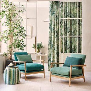 Modern living room with teal armchairs, ottoman, and decorative plants.