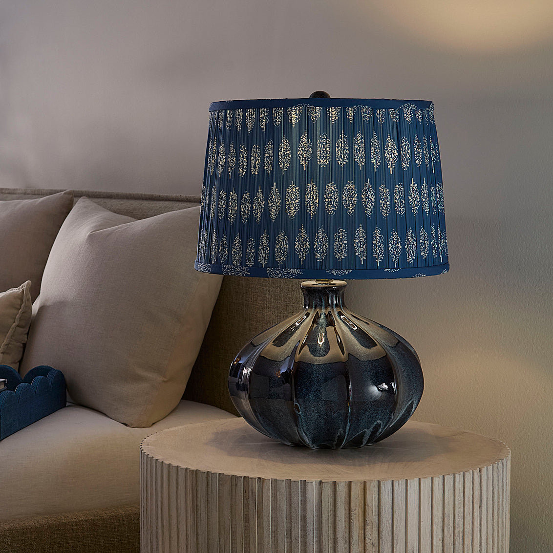Decorative lamp with a blue patterned shade on a side table next to a sofa.