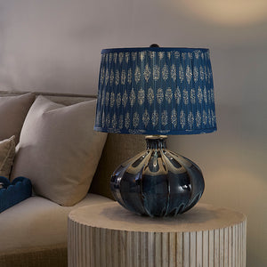 Decorative lamp with a blue patterned shade on a side table next to a sofa.
