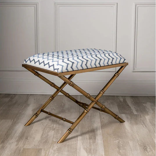 Brass Bamboo stool with a patterned cushion on a wooden floor against a gray paneled wall.