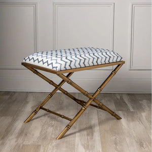 Brass Bamboo stool with a patterned cushion on a wooden floor against a gray paneled wall.