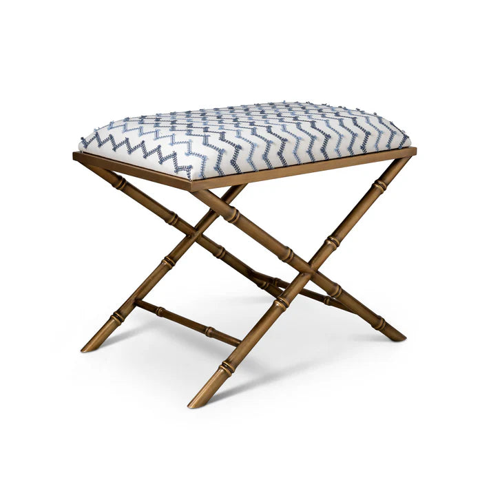 Brass X-stool with a patterned cushion on a white background