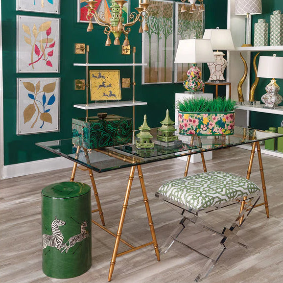 Decorative interior with a glass table, gold chairs, and colorful wall art.