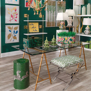 Decorative interior with a glass table, gold chairs, and colorful wall art.