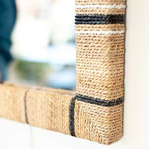 Woven mirror frame with black accents on a white surface