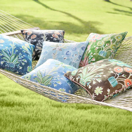 Hammock with colorful pillows on a grassy area by a lake