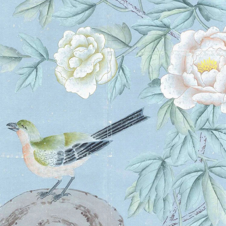 A traditional-style botanical illustration featuring pale blue-green leaves, large white and blush flowers, and a small bird perched on a tree stump against a soft light blue background.