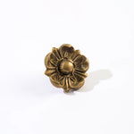 A single ornate flower-shaped decorative object with a textured metallic finish, photographed on a clean white background with a soft shadow.