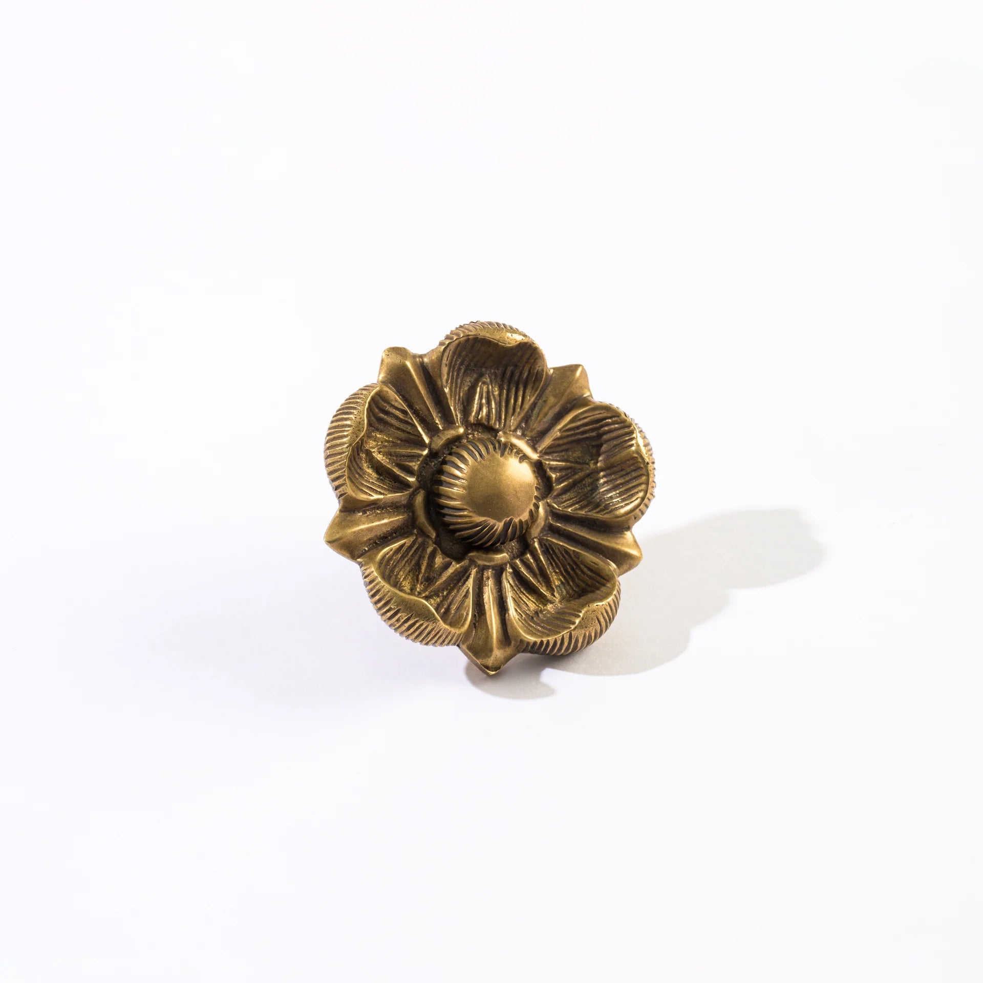 A single ornate flower-shaped decorative object with a textured metallic finish, photographed on a clean white background with a soft shadow.
