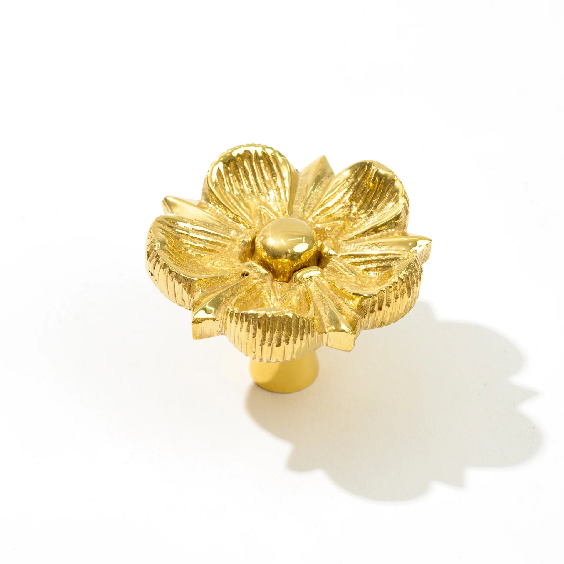 A single gold flower-shaped cabinet knob with textured petals and a polished center, shown on a white background with a soft shadow.
