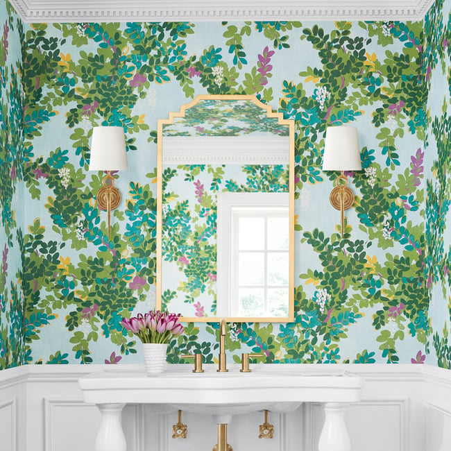 Decorative wall with floral wallpaper, mirror, and wall sconces.