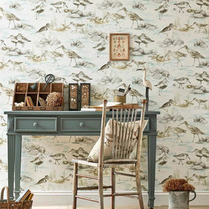 Room with a desk and chair against a wall with bird-themed wallpaper
