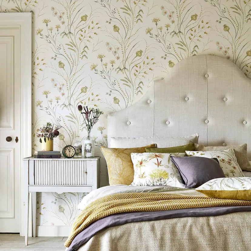 Bed with decorative pillows against a floral wallpapered wall.