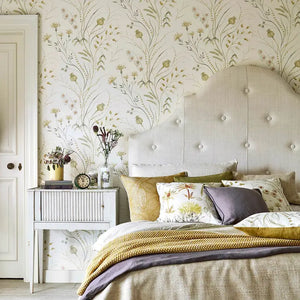 Bed with decorative pillows against a floral wallpapered wall.