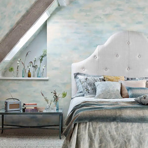 Modern bedroom with a bed, side table, and decorative elements featuring a cloud inspired wallpaper 