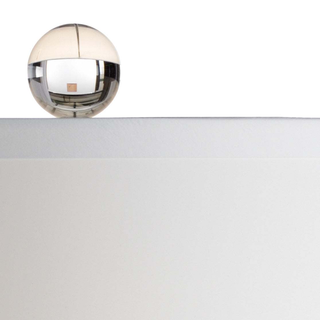 Clear glass finial with a reflective surface on a white background