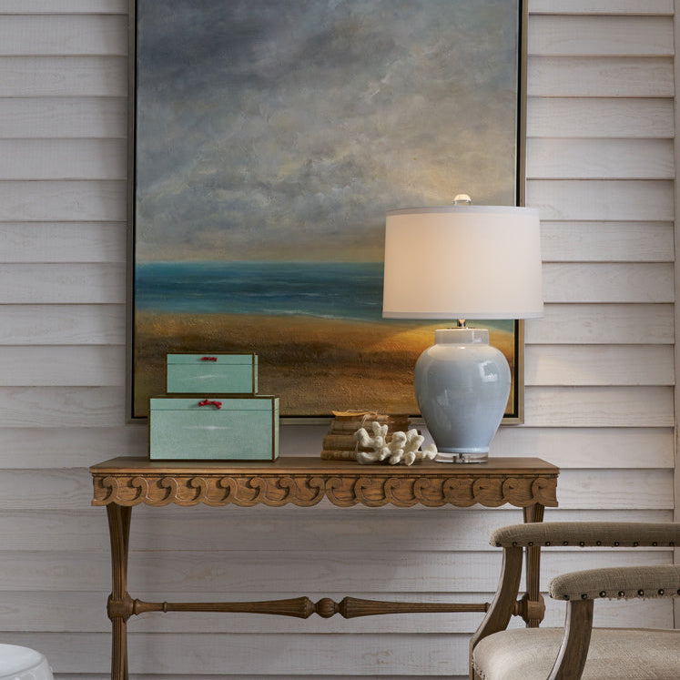 Room interior with a console table, lamp, and artwork on a wooden wall.