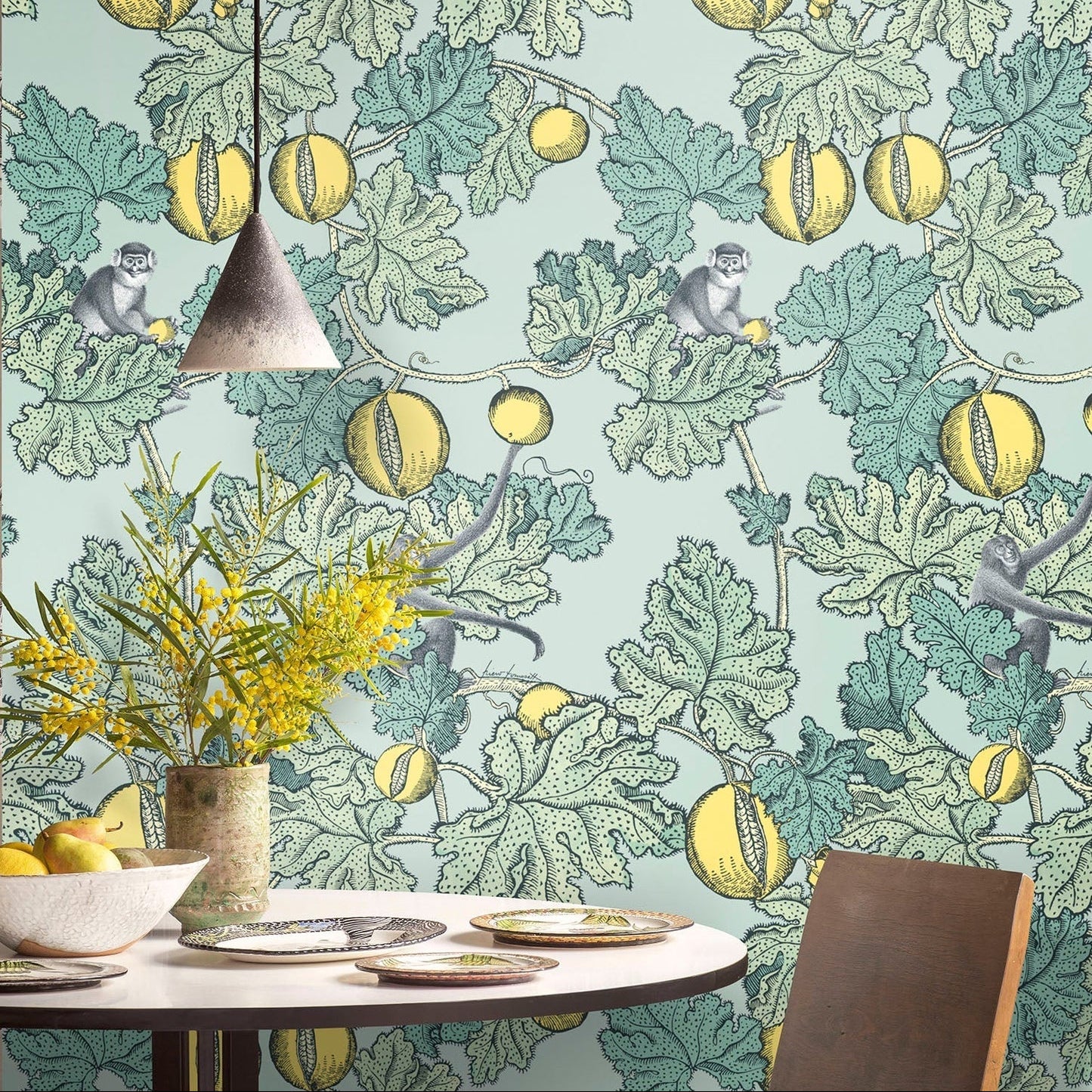 Dining room with a wallpaper featuring monkeys, melons, and leaves on a light blue background.