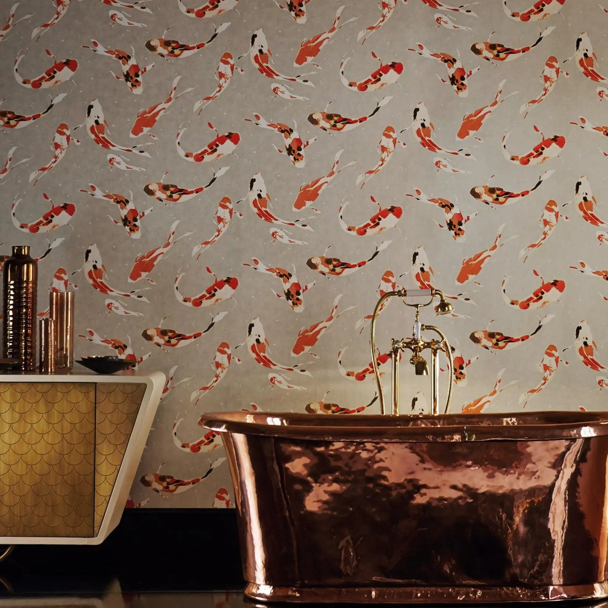 A freestanding copper bathtub in a styled bathroom setting, set against wallpaper featuring a repeating pattern of orange, white, and black koi fish on a light gray background.