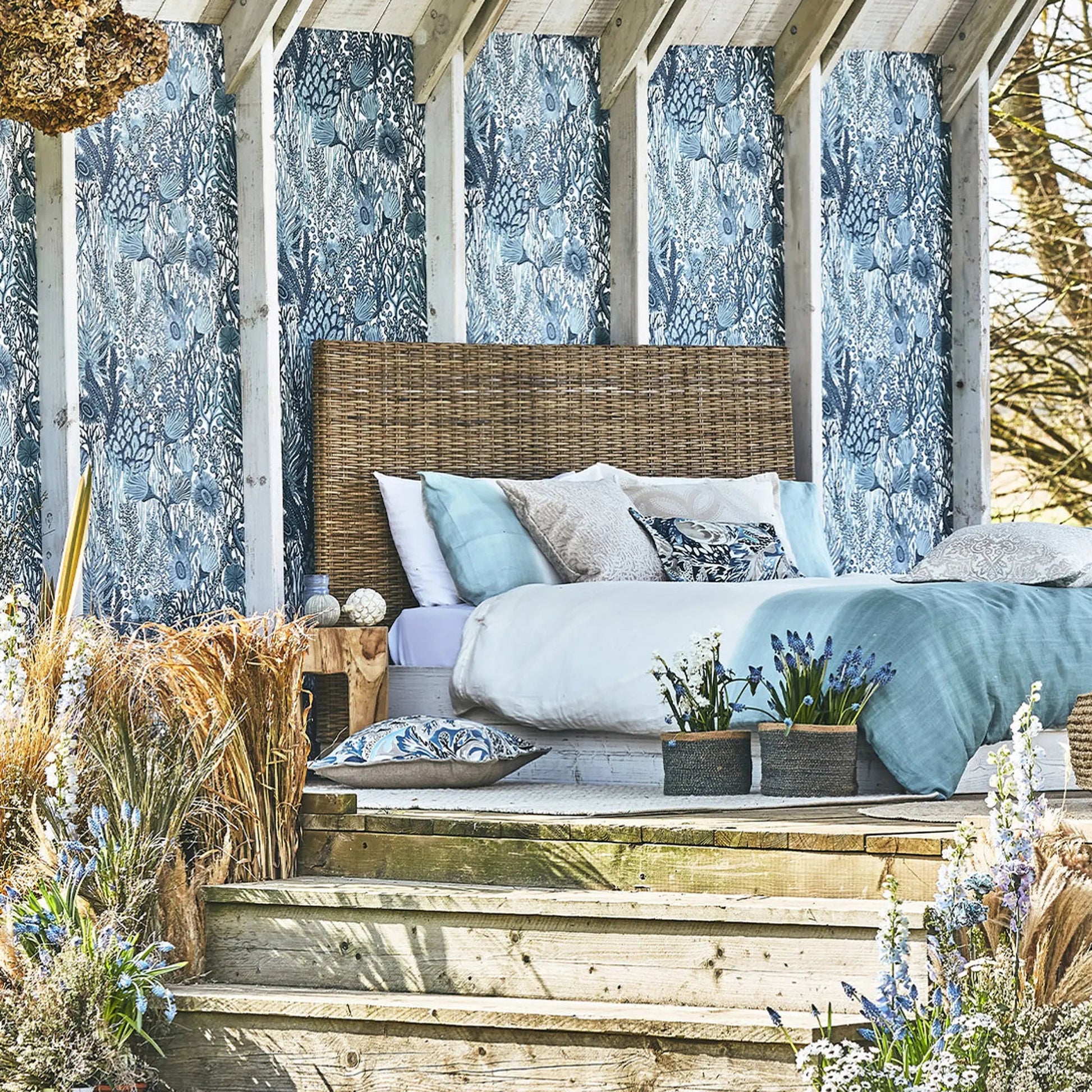 Bedroom with wooden headboard and blue bedding, surrounded by natural elements.