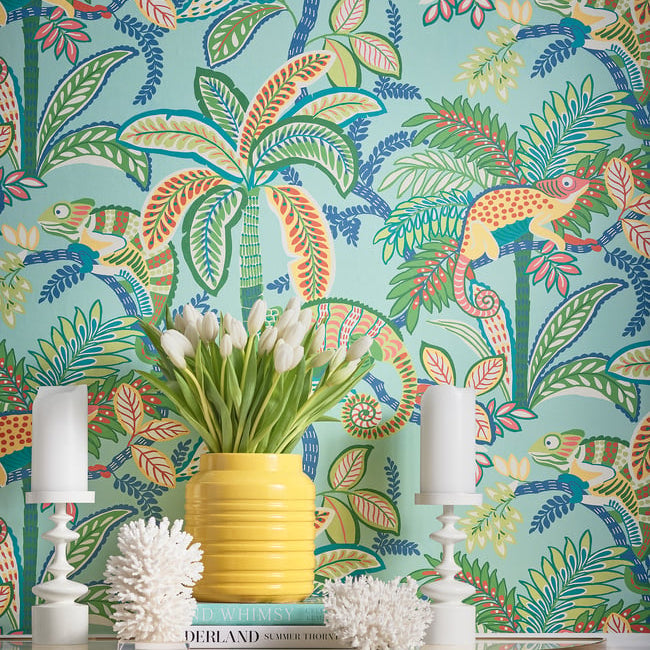 Colorful tropical wallpaper with palm trees, birds, and lizards, featuring a yellow vase with white tulips on a table.