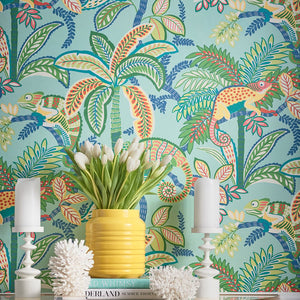 Colorful tropical wallpaper with palm trees, birds, and lizards, featuring a yellow vase with white tulips on a table.