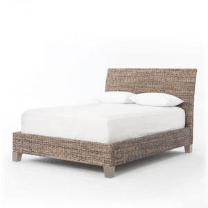 A woven seagrass bed shown with white bedding
