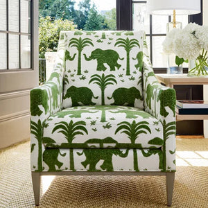 Chair with green elephant pattern in a room with large windows and a lamp.