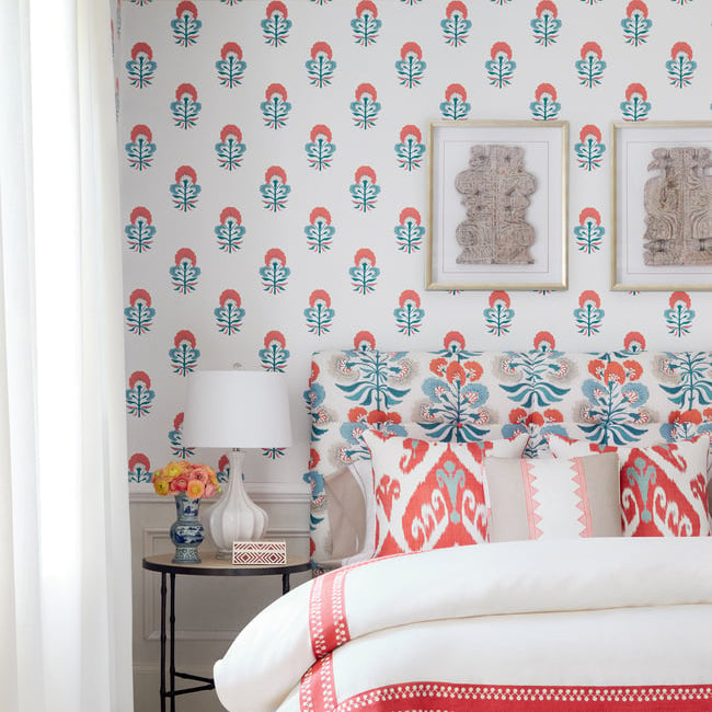 Bedroom with floral wallpaper, bed with red and white bedding, and side table with lamp.