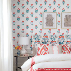 Bedroom with floral wallpaper, bed with red and white bedding, and side table with lamp.