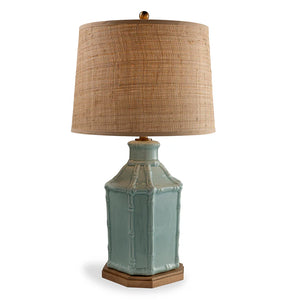 Table lamp with a textured green base and woven beige shade on a white background