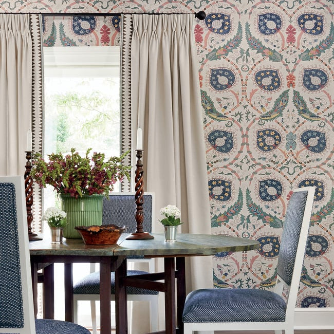 Dining room with patterned wallpaper, floral arrangement, and wooden table.