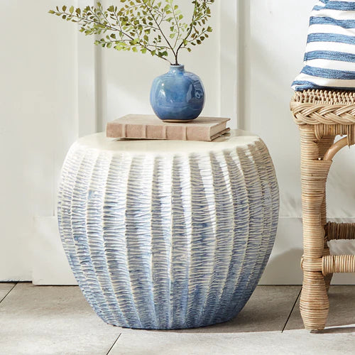 Decorative side table with blue and white striped pattern, featuring a blue vase and book on top.