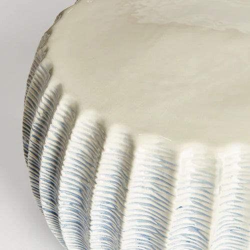 Close-up of a ceramic stool with blue line patterns on a white background