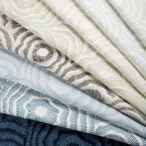 Stack of fabric swatches with geometric patterns in neutral colors.