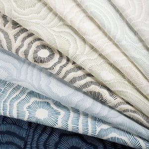 Stack of fabric swatches with geometric patterns in neutral colors.