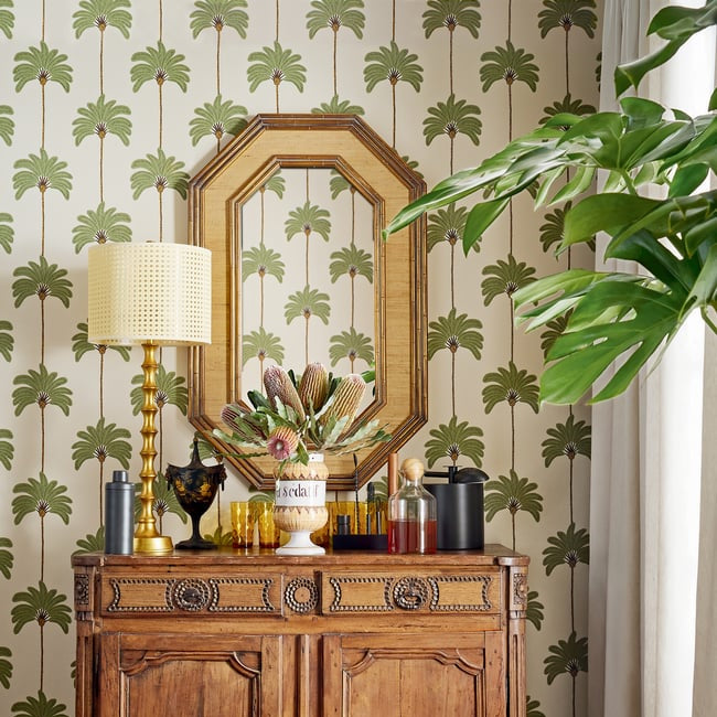Wooden sideboard with decorative items against a patterned wallpaper