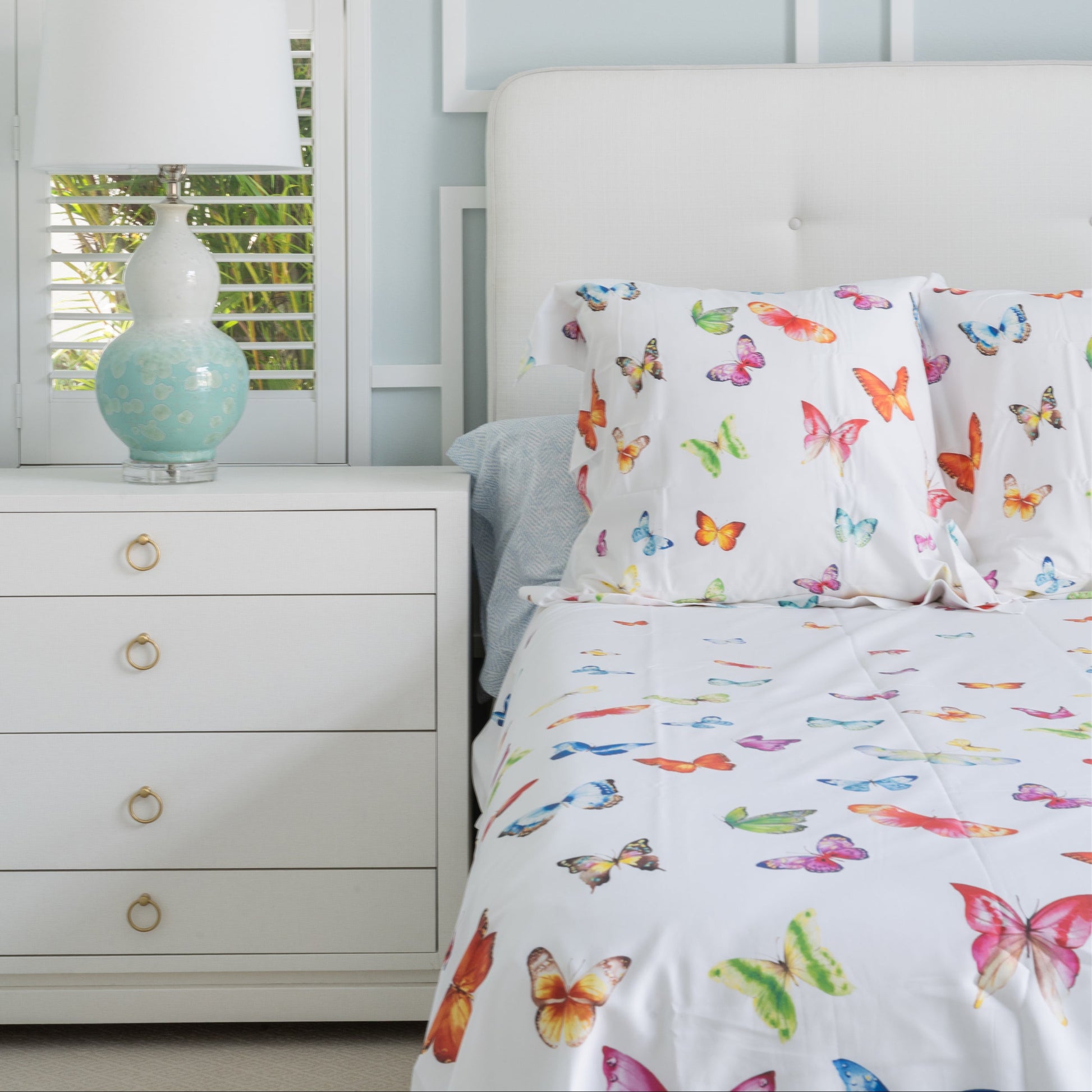 Bedroom with butterfly-patterned bedding and a white dresser.