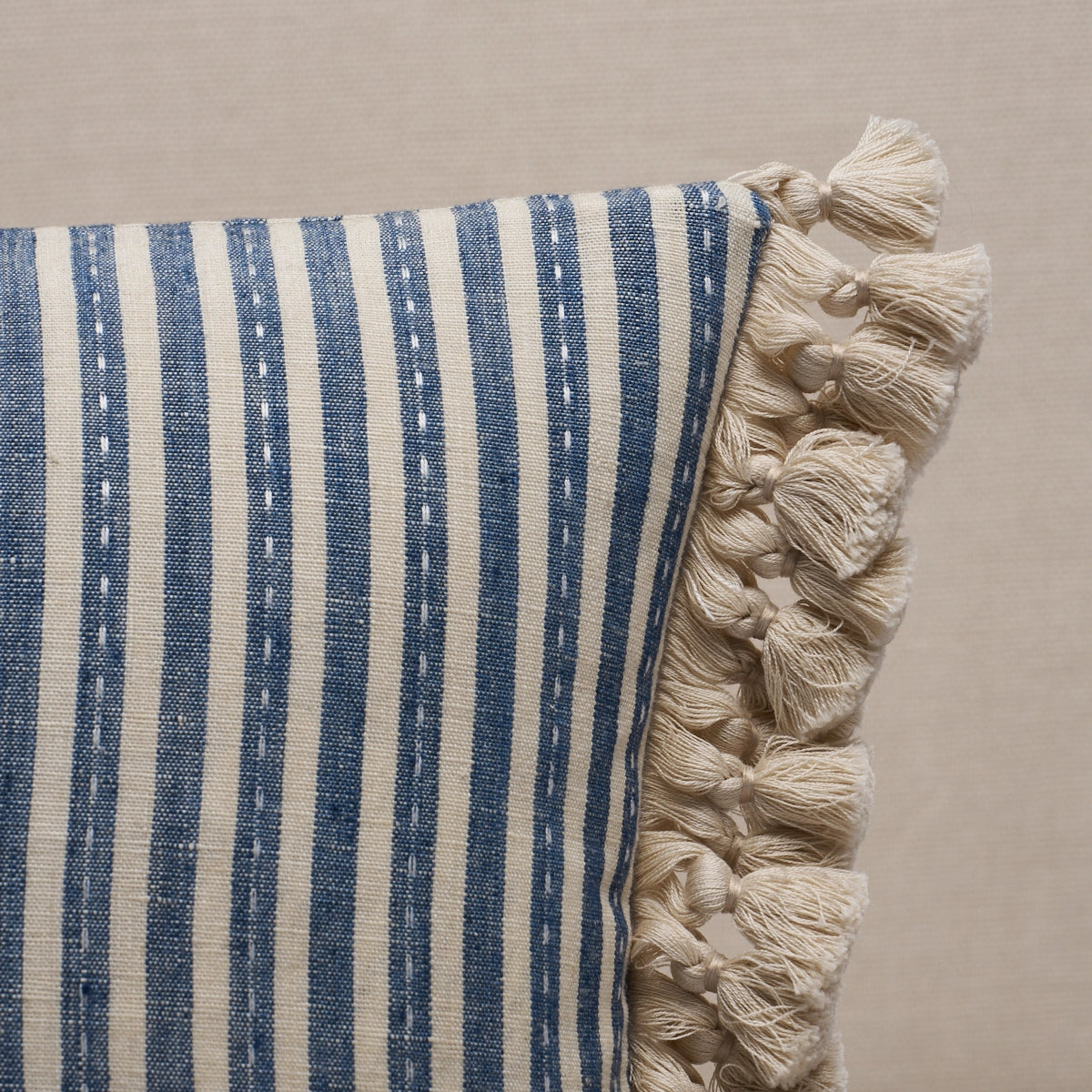 Striped pillow with tassels on a beige background