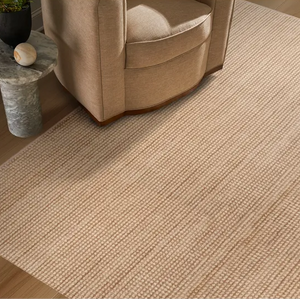 Neutral rug featured with a chair and side table  