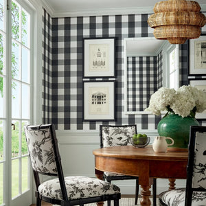 Dining room with checkered wall, wooden table, and floral chairs.