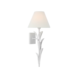 A white wall sconce with a sculptural leaf-like metal frame and a tapered white fabric shade, shown lit against a plain white background.